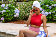 woman sitting by the pool wearing a hair towel